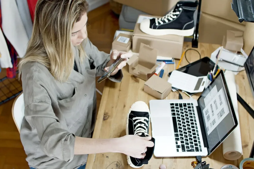 Online shop owner preparing products for sale with a laptop